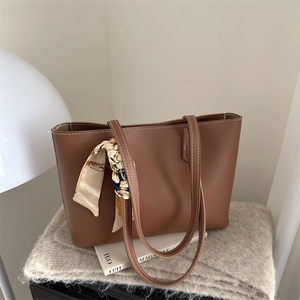 Brown leather tote bag with silk scarf decoration and white contrast stitching detail