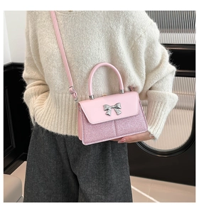 Detail view of pink glitter and smooth leather crossbody bag with silver bow ornament