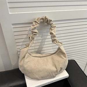 Minimalist beige hobo bag with pleated handle and matte finish in indoor setting