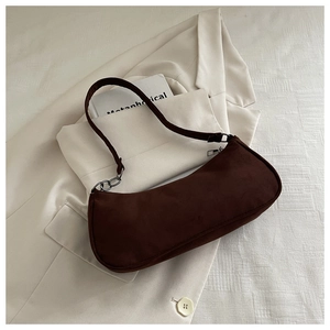 Detail of dark brown suede baguette bag with chic silver chain strap and matte finish
