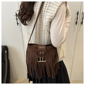 Détail du sac bandoulière en daim marron avec de longues franges et boucles argentées