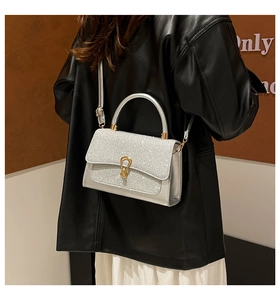 Detail of silver sequin handbag with gold U-shaped buckle and metallic handle