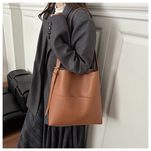 Detailed view of caramel leather tote bag with adjustable strap worn by model