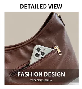 Detail of dark brown pebble leather crossbody bag showing functional zipper pocket with phone