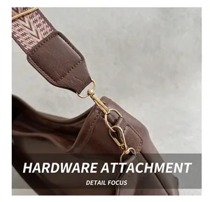 Detailed close-up of golden metal hooks and woven strap on a brown vintage handbag
