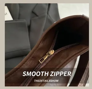Detailed close-up of smooth gold metal zipper on a premium dark brown leather handbag