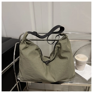 Détail du sac bandoulière en nylon vert olive avec sangle noire et double fermeture éclair