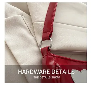 Close-up of shiny red patent leather bag with silver metal ring and heart stitching detail