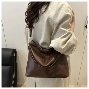Détail du sac cabas en cuir marron avec bandoulière réglable et crochets métalliques