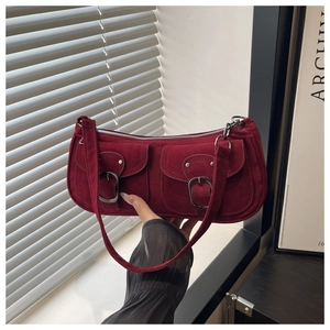 Detail of burgundy suede underarm bag featuring dual pockets and silver metal buckles