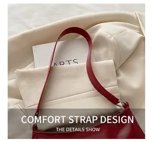 Detail of red glossy leather shoulder bag with silver round metal buckle and wide strap