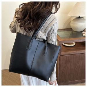 Detailed back view of a minimalist large black tote bag on a shoulder for daily commute