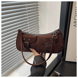 Macro shot of dark brown suede shoulder bag featuring retro metal buckle pockets