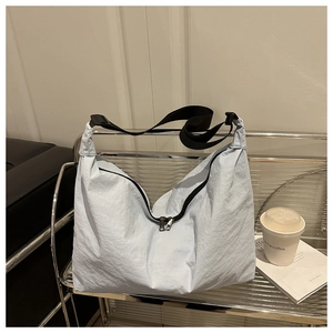 Détail du sac hobo bleu clair en nylon avec bandoulière noire sur étagère en métal