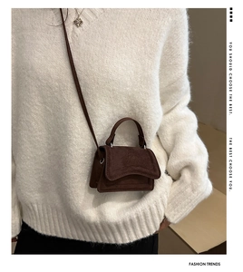 Close-up of a mini dark brown faux suede crossbody bag with flap and thin strap