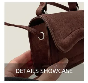 Close-up of silver metal eyelets and fine stitching on brown suede crossbody bag