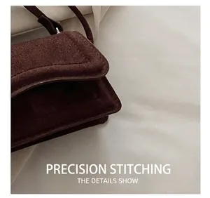 Macro shot of precise stitching on dark brown suede crossbody bag showing leather detail