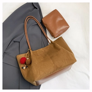 Détail du sac fourre-tout en daim avec pochette et charmes en peluche sur fond neutre