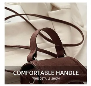 Detail showing the curved top handle and faux suede texture of the dark brown mini handbag