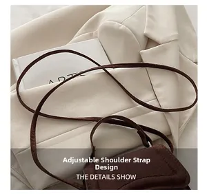 Detail of adjustable shoulder strap design on a brown suede crossbody square bag