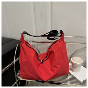 Détail du sac cabas en nylon rouge avec bandoulière noire réglable et fermeture éclair