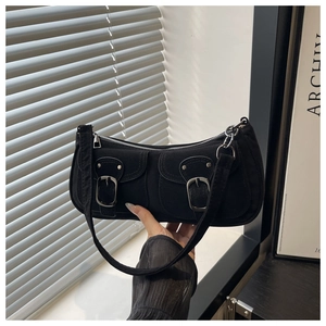 Detail of black suede shoulder bag with dual front pockets and silver buckles