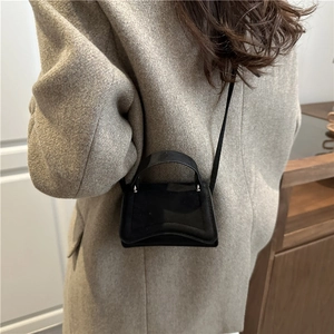 Chic black mini crossbody bag with irregular curved design on model in a wool coat