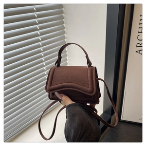 Detail of a dark brown mini crossbody bag with soft matte texture and top handle
