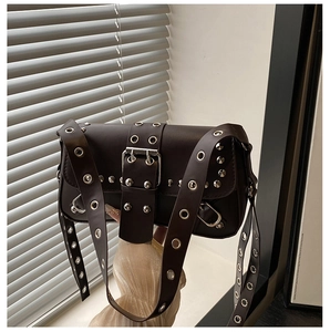 Close-up of metallic eyelets and silver rivets on dark punk-style leather shoulder bag