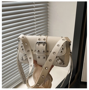 Detail of cream leather shoulder bag with punk rivets and silver eyelet strap detail