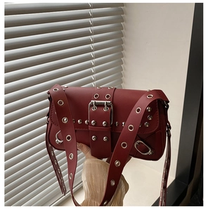 Detail of burgundy biker shoulder bag with silver grommets and metallic buckle strap