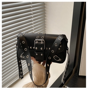 Close-up of black punk style shoulder bag with silver studs and large metal grommet detail