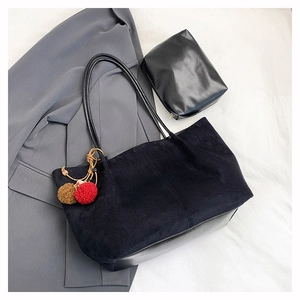 Gros plan d'un grand sac cabas noir en velours côtelé avec pompons et pochette assortie