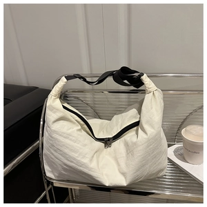 Détail d'un sac cabas en nylon blanc avec bandoulières noires et zips argentés élégants