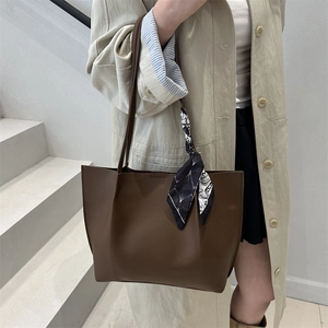 Fashionable dark brown leather pleated tote bag with scarf detail worn by a model