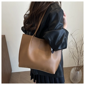 Detailed back view of a large brown tote bag worn with a black leather jacket