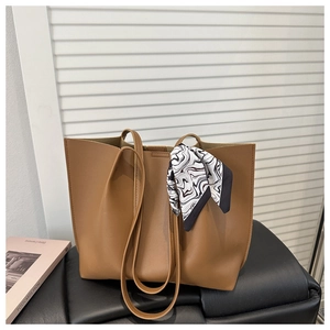 Detail view of caramel brown tote bag with silk scarf decoration and high-quality leather texture