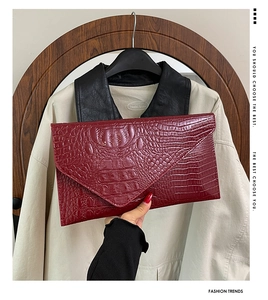 Detailansicht der weinroten Clutch in Krokodiloptik mit Umschlag und eleganter Metallkette
