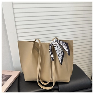 Detail of beige large tote bag featuring elegant black and white silk scarf on the handle