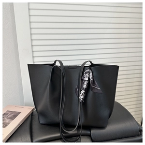Detail of black faux leather tote bag with geometric print scarf and slim shoulder straps