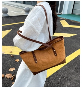 Detail of brown quilted shoulder bag with suede texture and metallic rivet accents