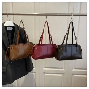 Three vintage leather underarm bags in brown, red and coffee hanging on a display rack