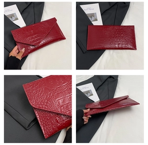 Detail der roten Briefumschlag-Clutch mit Krokodil-Prägung und glänzendem Finish