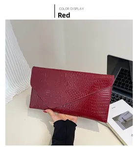 Detailaufnahme einer roten Clutch aus geprägtem Krokodilleder im Briefumschlag-Stil