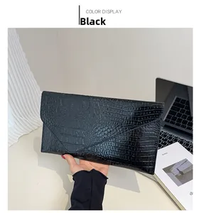 Detail der schwarzen Umschlag-Clutch mit glänzender Kroko-Prägung in der Hand gehalten
