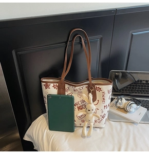 Détail du sac cabas blanc à graffitis avec anses en cuir marron et pendentif lapin