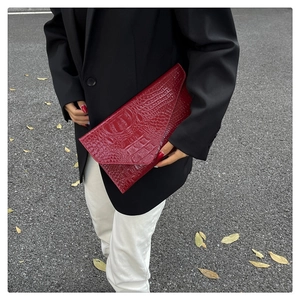 Detail of dark red envelope clutch bag featuring luxury crocodile texture leather