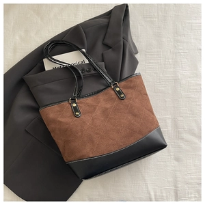 Detail of brown quilted tote bag with black straps and golden metal hardware on a blazer