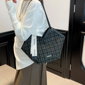Tweed tote bag with black and yellow patterns and leather handles on model shoulder
