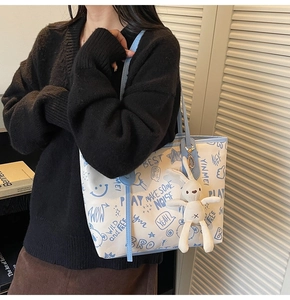 Détail du sac cabas graffiti blanc avec lettrage bleu et breloque lapin en peluche